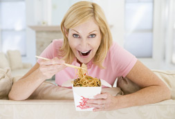 Smiling woman eating Chinese food with chop-sticks